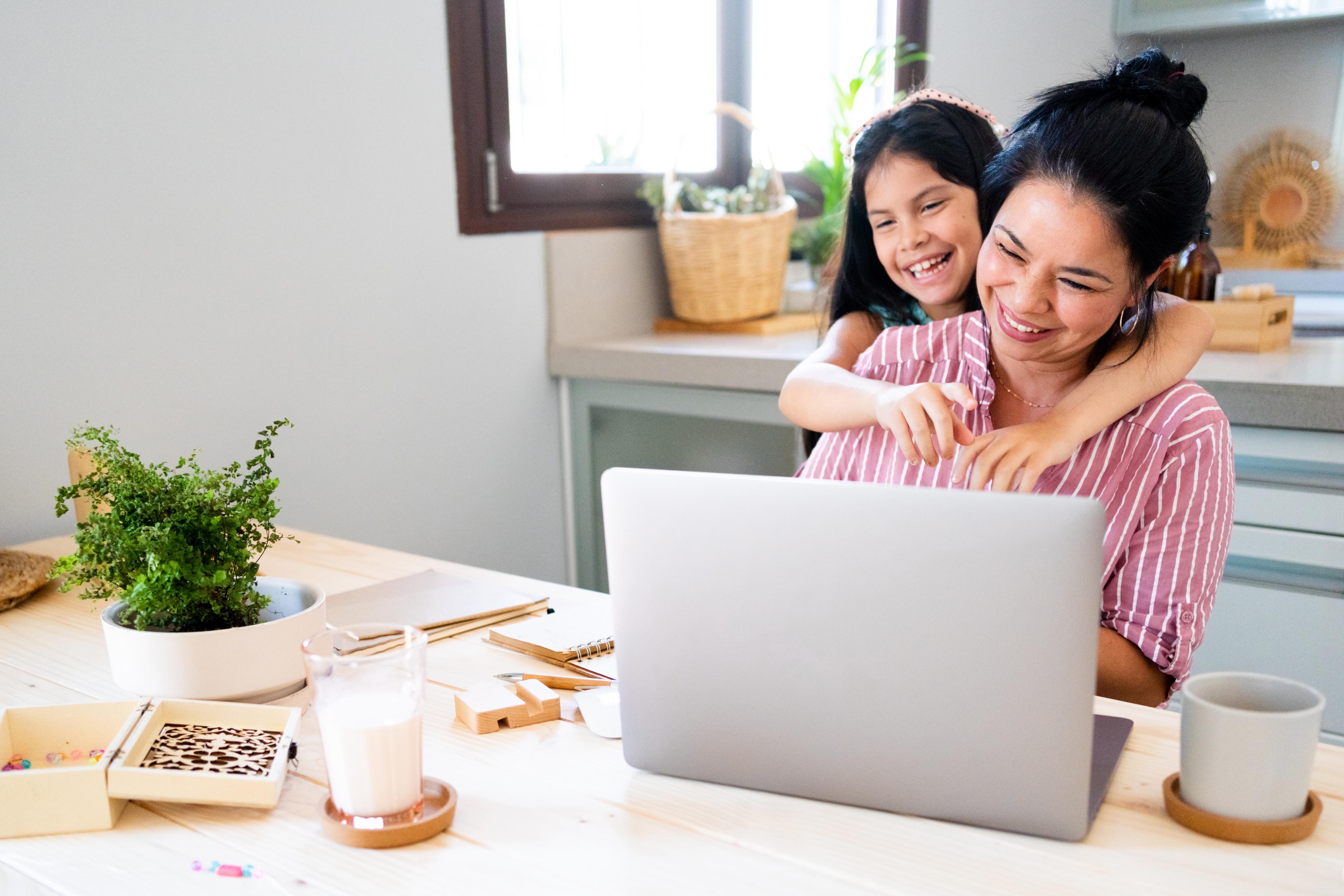Une maman et sa fille qui sourient en regardant leur ordinateur portable pendant un appel virtuel avec leur diététiste.